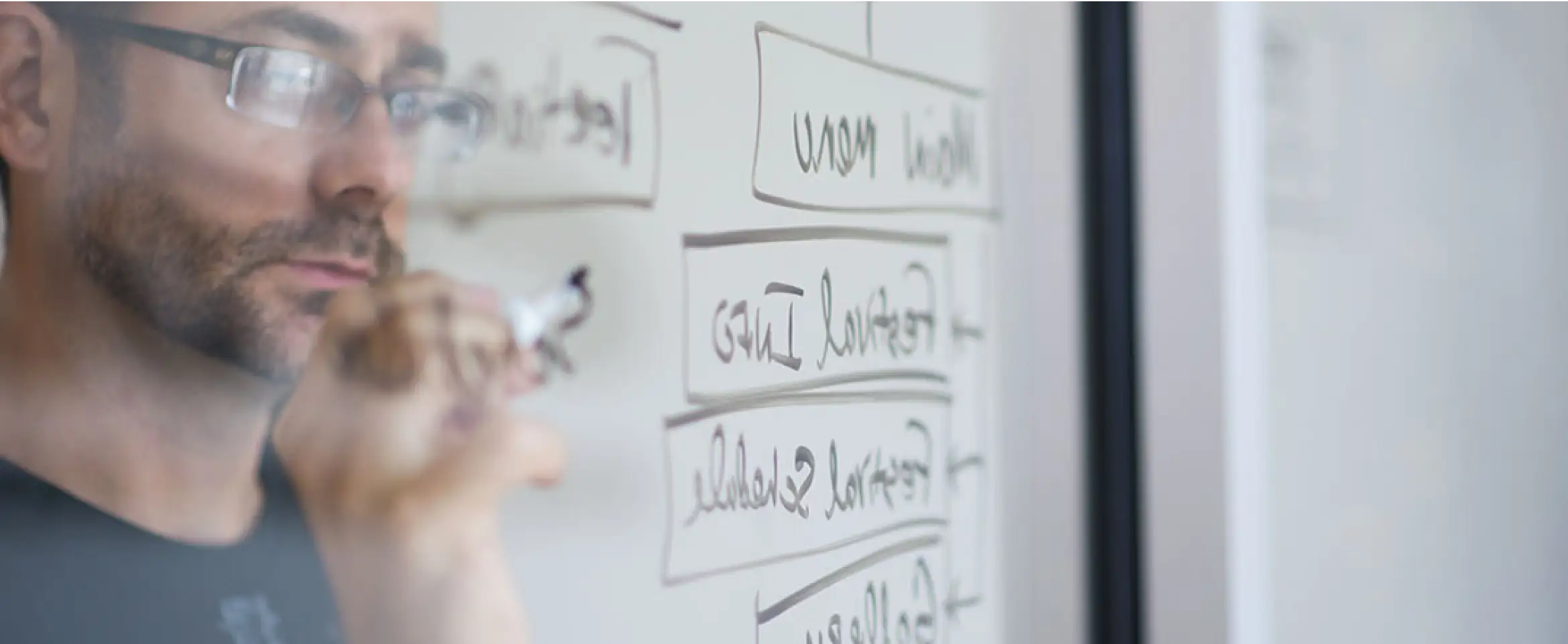 An Evolve team member writes on glass board during brain storm session.